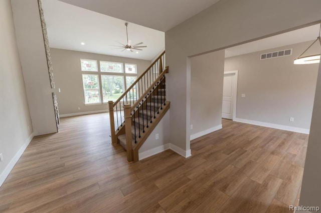 staircase with ceiling fan and wood-type flooring