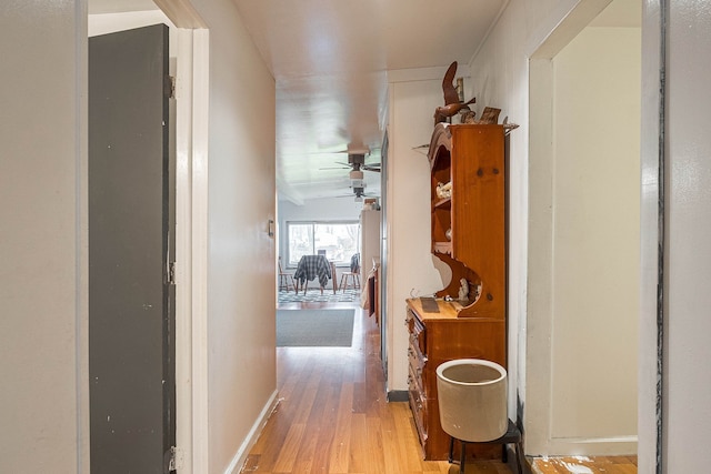 hallway with light wood-type flooring and vaulted ceiling