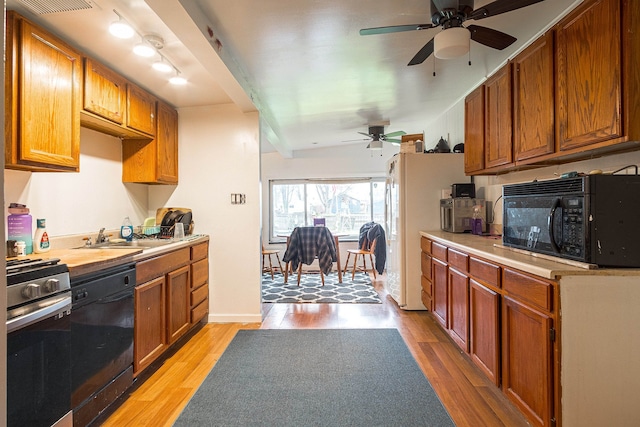 kitchen featuring sink, light wood-type flooring, ceiling fan, and black appliances