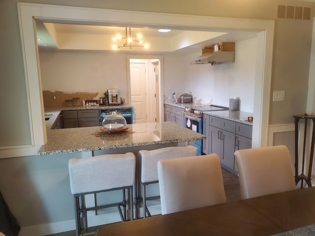 kitchen with pendant lighting, exhaust hood, stainless steel electric stove, kitchen peninsula, and a breakfast bar area