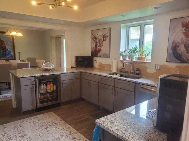 kitchen with sink, dark hardwood / wood-style floors, light stone counters, kitchen peninsula, and beverage cooler