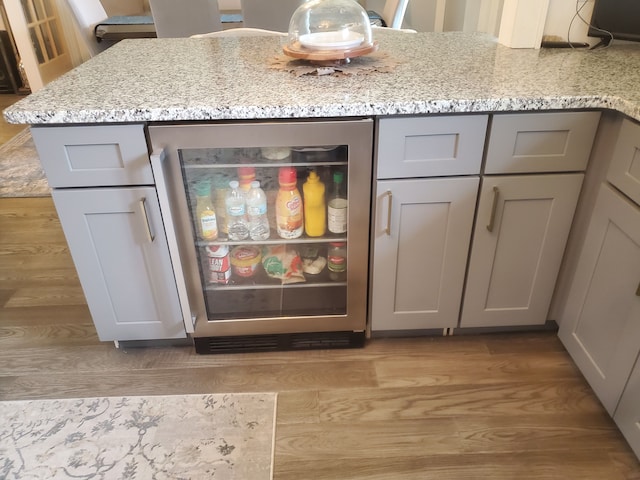 interior details with gray cabinetry, light stone countertops, light wood-type flooring, and wine cooler