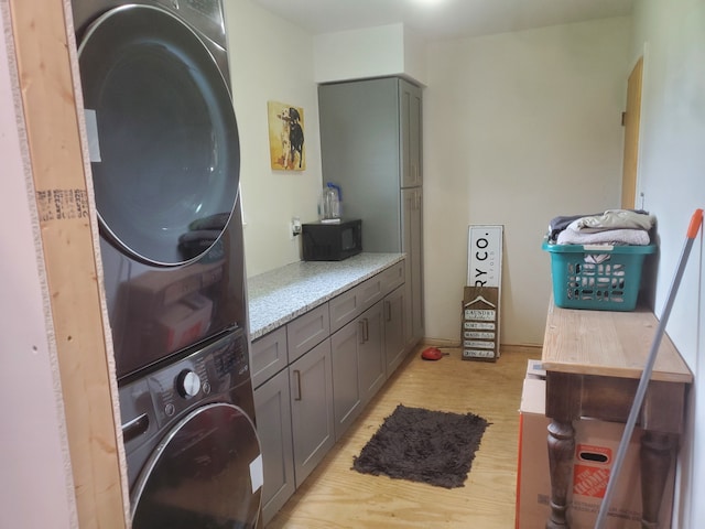 laundry room with cabinets and stacked washer and clothes dryer