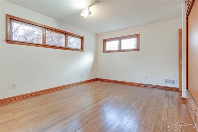 empty room featuring track lighting and light wood-type flooring