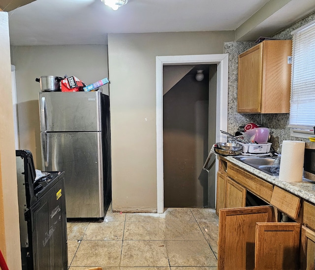 19356 Huntington Rd, Detroit, MI 48219 - kitchen with freestanding refrigerator, black range with electric stovetop, a sink, light countertops, and brown cabinetry