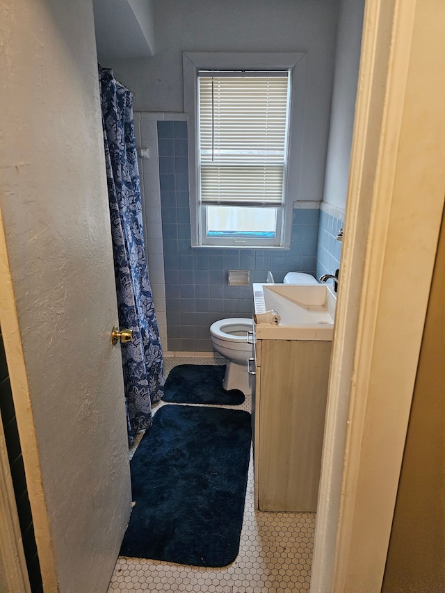 19356 Huntington Rd, Detroit, MI 48219 - bathroom featuring tile patterned floors, vanity, toilet, tile walls, and a wainscoted wall