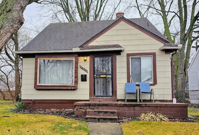 19356 Huntington Rd, Detroit, MI 48219 - view of front of home with a shingled roof, a chimney, a front yard, and a porch