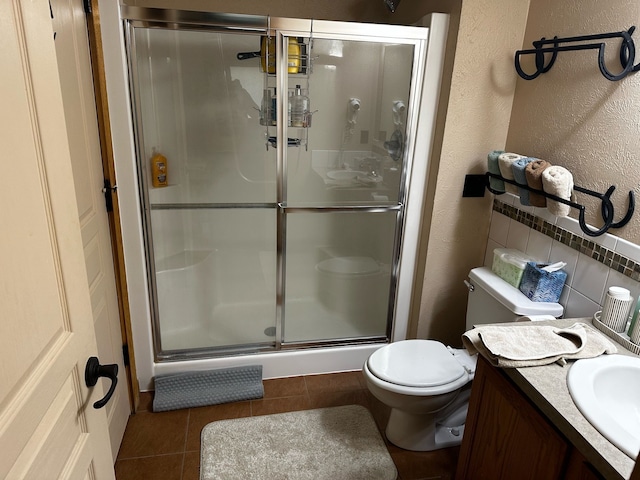 bathroom with tile patterned flooring, vanity, toilet, and walk in shower