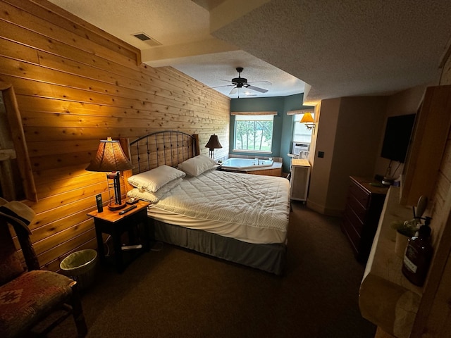 bedroom with ceiling fan, dark carpet, a textured ceiling, and wooden walls