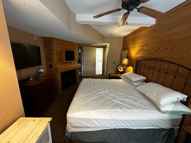 bedroom featuring a fireplace, a textured ceiling, ceiling fan, and wooden walls