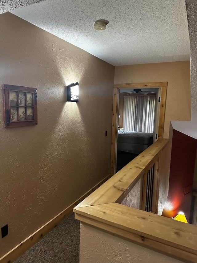 hallway with carpet flooring and a textured ceiling