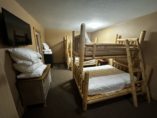 bedroom with dark colored carpet and a textured ceiling