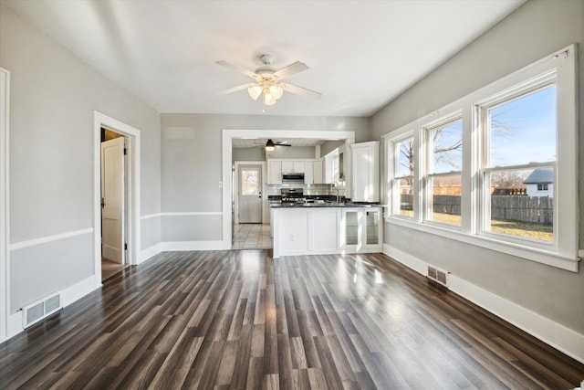 unfurnished living room featuring dark hardwood / wood-style flooring, ceiling fan, and sink