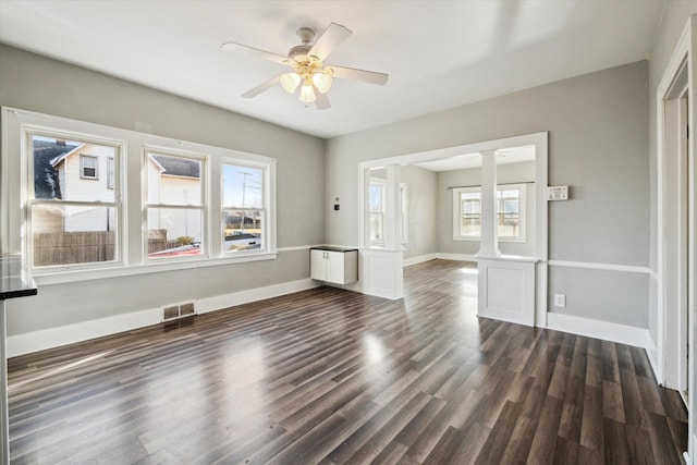 interior space featuring decorative columns, radiator, ceiling fan, and dark hardwood / wood-style floors