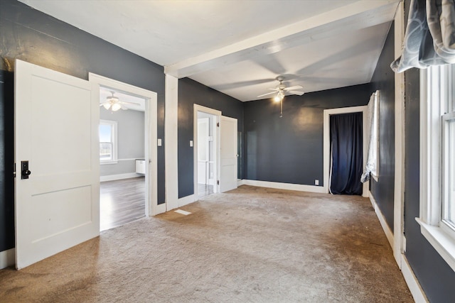 carpeted empty room featuring beam ceiling and ceiling fan