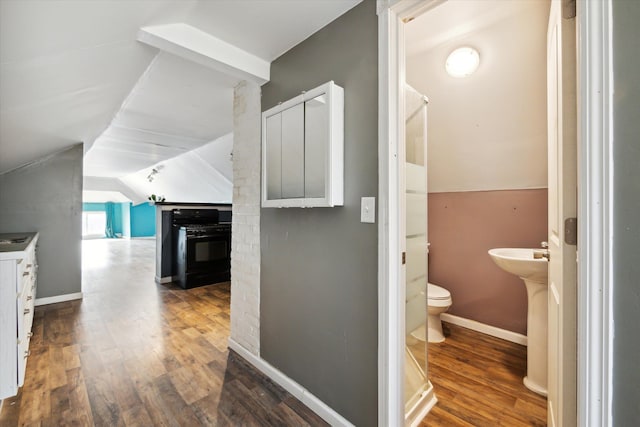 corridor with vaulted ceiling and hardwood / wood-style flooring