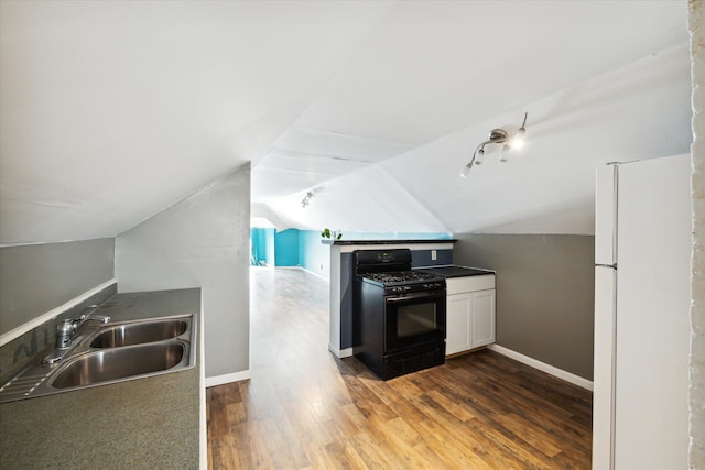 kitchen featuring black gas range, sink, white refrigerator, vaulted ceiling, and white cabinets