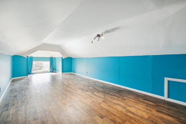 additional living space featuring wood-type flooring and vaulted ceiling