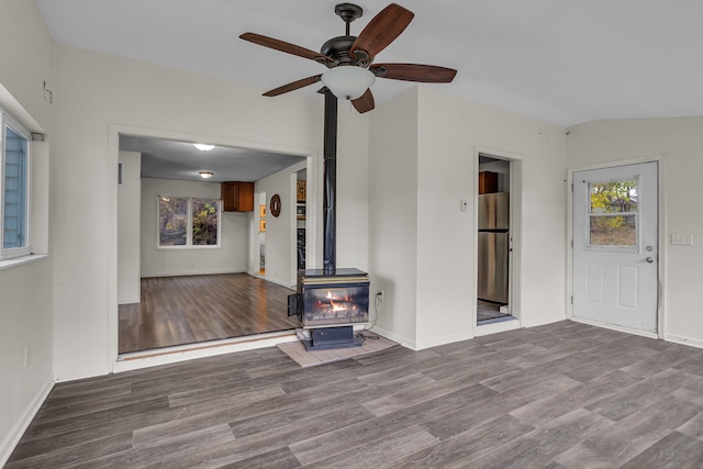 unfurnished living room featuring hardwood / wood-style floors, vaulted ceiling, a wood stove, and ceiling fan