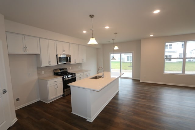 kitchen with pendant lighting, sink, an island with sink, appliances with stainless steel finishes, and dark hardwood / wood-style flooring