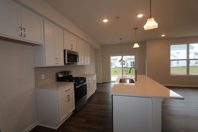 kitchen with sink, hanging light fixtures, an island with sink, white cabinets, and appliances with stainless steel finishes