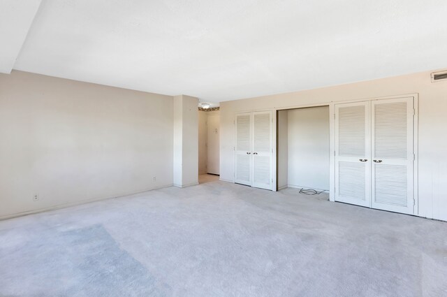 8900 E Jefferson Ave Unit 630-631, Detroit, MI 48214 - unfurnished bedroom featuring multiple closets, light carpet, and baseboards