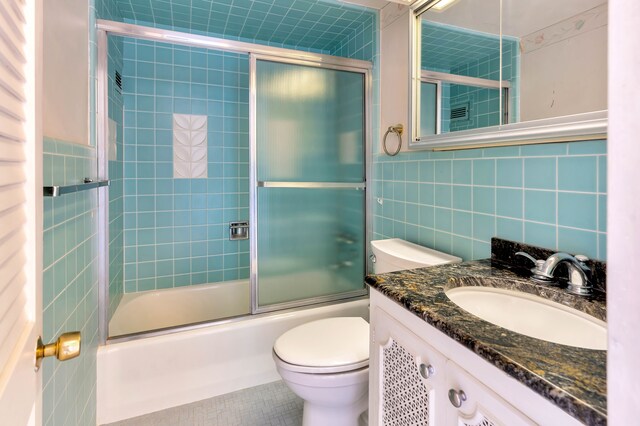 8900 E Jefferson Ave Unit 630-631, Detroit, MI 48214 - bathroom featuring tile walls, toilet, combined bath / shower with glass door, vanity, and tile patterned flooring
