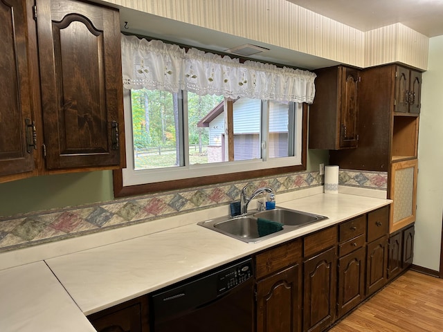 kitchen with light wood-type flooring, dark brown cabinets, black dishwasher, and sink