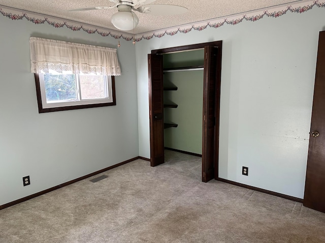 unfurnished bedroom with ceiling fan, a closet, light carpet, and a textured ceiling