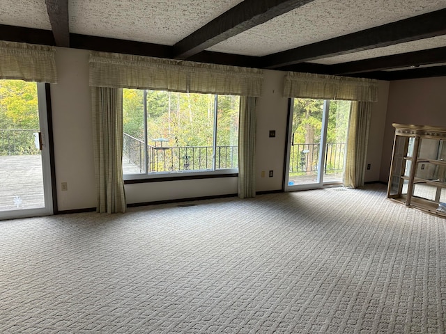 spare room with carpet flooring, beamed ceiling, and a textured ceiling