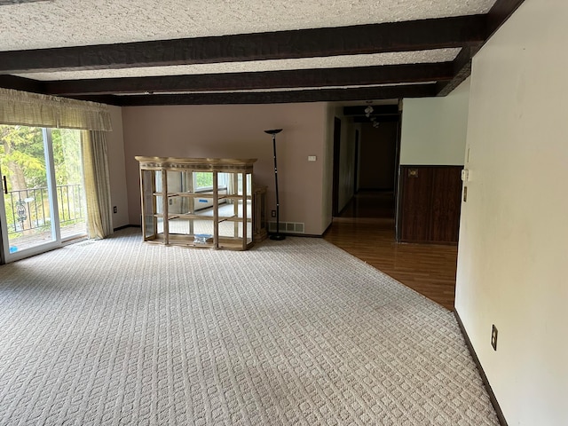 empty room featuring beamed ceiling, a textured ceiling, hardwood / wood-style flooring, and ceiling fan