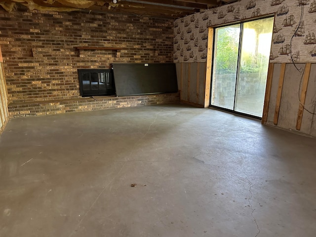 unfurnished living room with concrete floors and brick wall