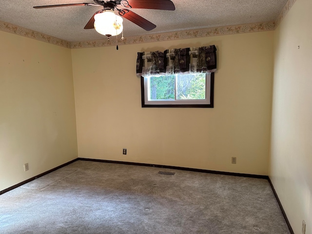 carpeted empty room with ceiling fan and a textured ceiling