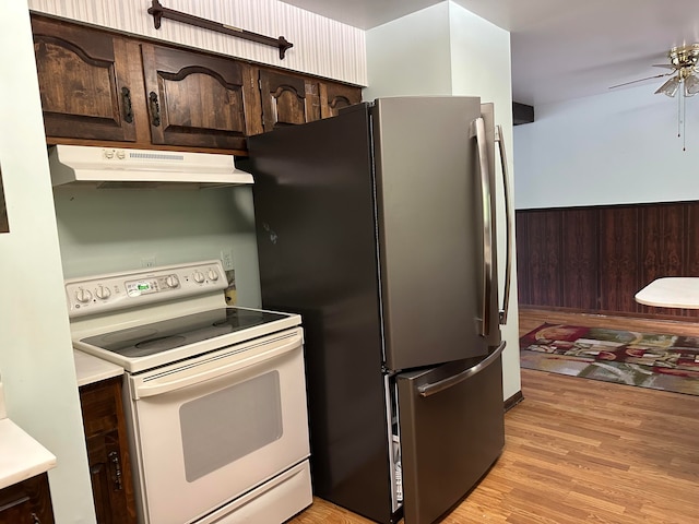 kitchen with wooden walls, electric range, light hardwood / wood-style floors, dark brown cabinetry, and stainless steel refrigerator