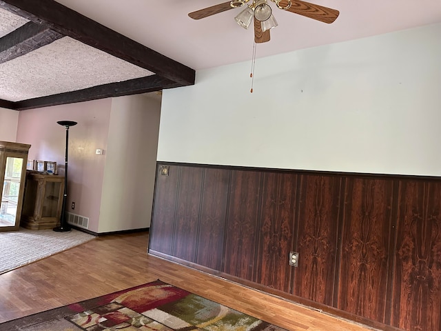 interior space with ceiling fan, beamed ceiling, and wood-type flooring