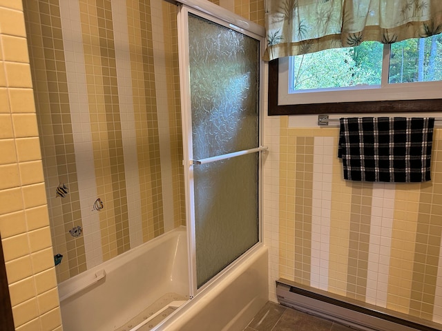 bathroom with shower / bath combination with glass door, tile patterned flooring, and baseboard heating