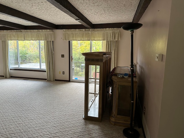 doorway featuring beam ceiling, carpet, and a textured ceiling