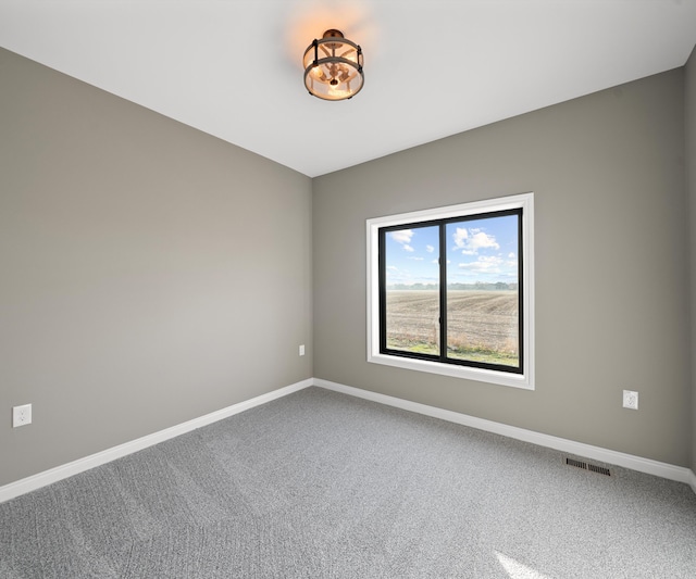 spare room featuring carpet, visible vents, and baseboards