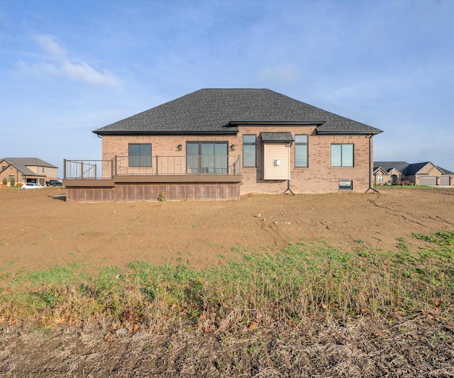 rear view of property featuring brick siding and roof with shingles