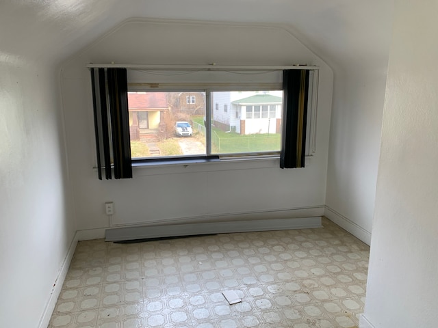 unfurnished room with vaulted ceiling and a baseboard heating unit