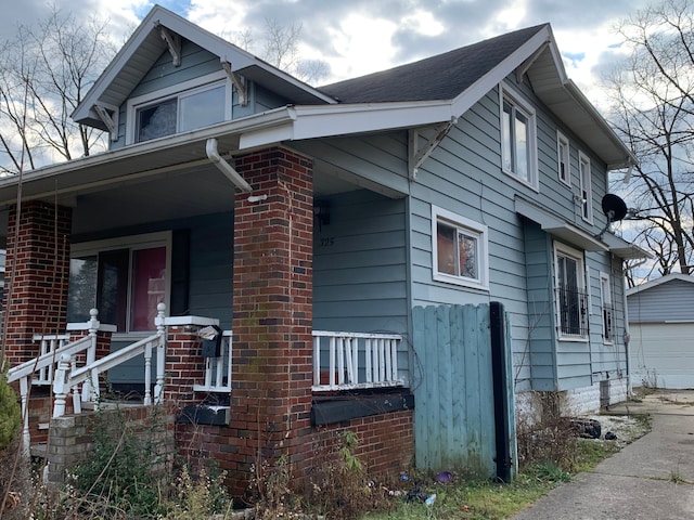 view of side of property featuring a porch, a garage, and an outdoor structure