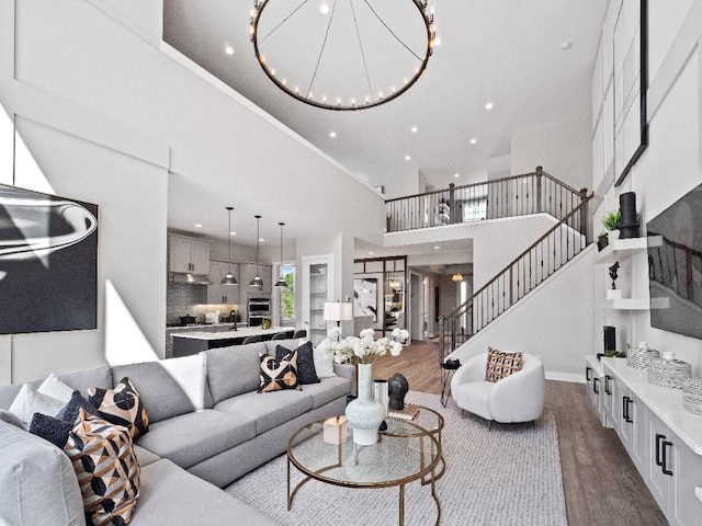 living room with wood-type flooring, a towering ceiling, and a chandelier