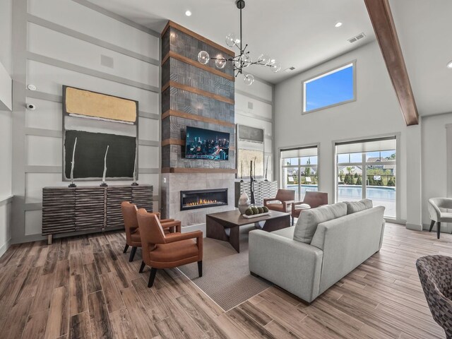 7889 Arimoore Dr, West Bloomfield, MI 48322 - living room with wood finished floors, a fireplace, a chandelier, a towering ceiling, and recessed lighting