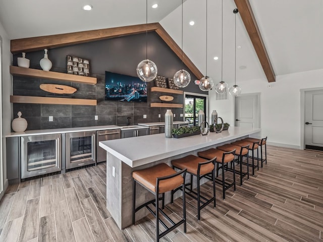 kitchen with a breakfast bar area, wine cooler, decorative light fixtures, and hardwood / wood-style flooring