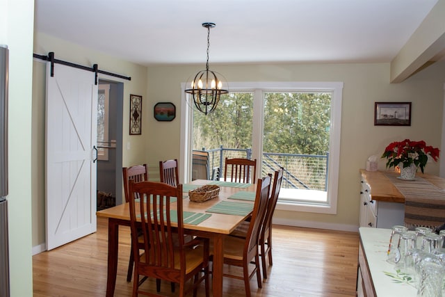 122 Park Ave, Frankfort, MI 49635 - dining room with a barn door, light wood-style flooring, baseboards, and a chandelier