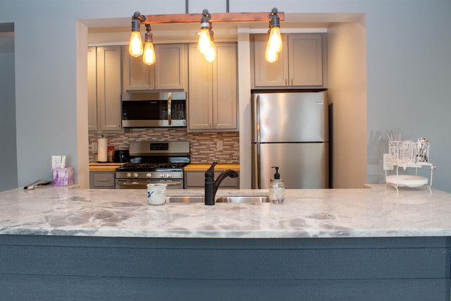 122 Park Ave, Frankfort, MI 49635 - kitchen with stainless steel appliances, a sink, decorative backsplash, and light stone countertops