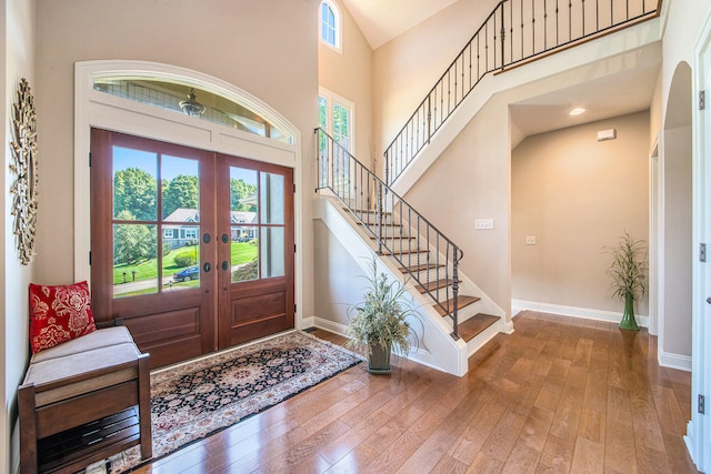 entryway featuring wood-type flooring, a high ceiling, and french doors