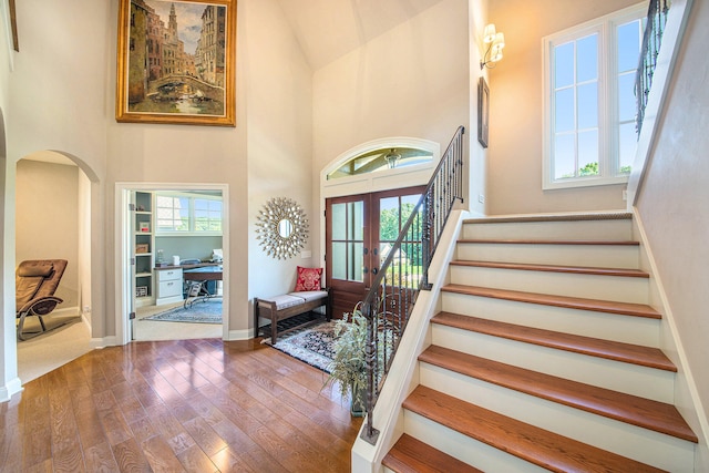 foyer entrance featuring hardwood / wood-style floors, a towering ceiling, and a healthy amount of sunlight