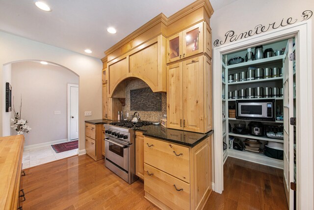 kitchen with butcher block counters, stainless steel appliances, backsplash, light brown cabinetry, and light wood-type flooring