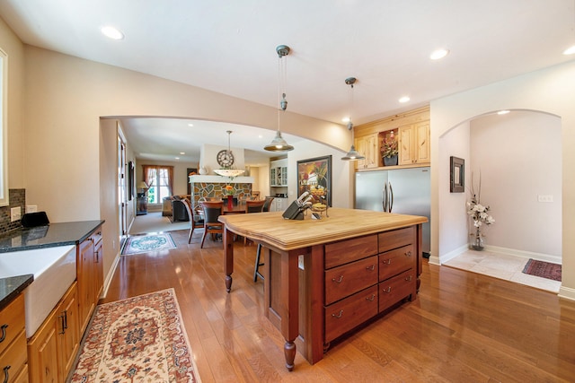 kitchen with stainless steel fridge, pendant lighting, and light wood-type flooring